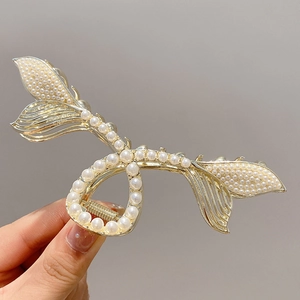 Détail d'une grande pince à cheveux dorée avec perles blanches et motif queue de poisson