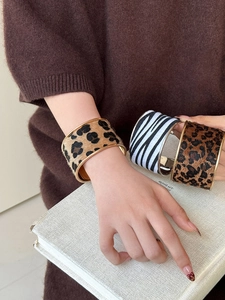 Détail de larges bracelets manchettes à motifs léopard et zèbre portés par un mannequin