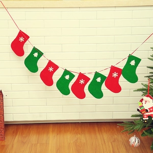 Christmas felt sock banner with red and green snowflake patterns on white brick wall