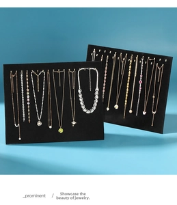 Detailed view of two black velvet necklace display stands with gold metal hooks