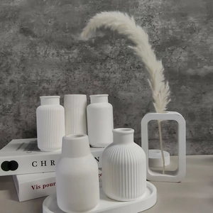 Detailed view of matte white ceramic vases with vertical stripes and modern shapes