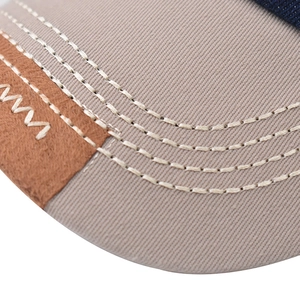 Detailed close-up of stitching on beige cotton brim and brown faux leather patch