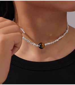 Close-up of minimalist tiger eye pendant on silver chain worn on a female collarbone