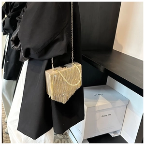Detail of a luxury gold fringe evening bag with shimmering metallic tassels and chain strap