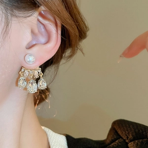 Close-up of pearl and teardrop crystal earrings in gold finish worn by a model