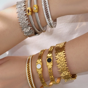 Elegantes brazaletes de acero chapados en oro 18k con circonitas 5A en el brazo del modelo