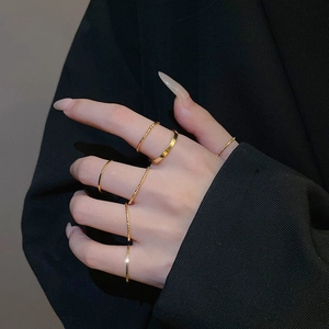 Close-up of six minimalist gold rings layered on a hand with twist and sleek band styles