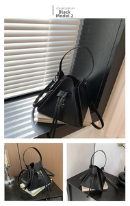 Detail of matte black triangular punk bag with silver skull charm and drawstring closure
