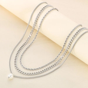Close-up of layered silver stainless steel necklace with pearl pendant and diverse chains