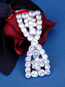 Close-up of sparkling cubic zirconia bow hair clip on premium red and black fabric