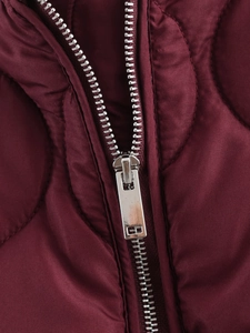 Macro shot of silver metal zipper and quilted burgundy fabric on the winter jacket
