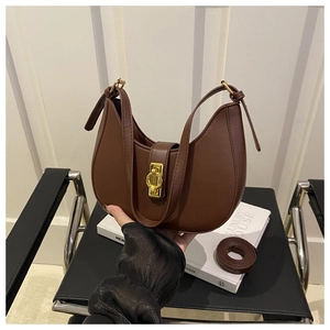 Detail of a brown leather crescent shoulder bag with golden buckle on a black chair