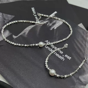 Detail of silver irregular metal beads and central white pearl on necklace and bracelet set