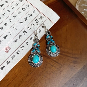 Macro shot of vintage silver leaf earrings with turquoise stones on dark wood