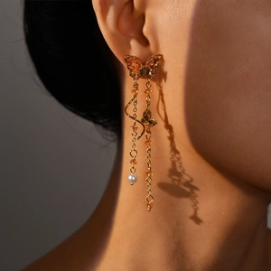 Detail of long butterfly tassel earrings with orange stones and pearls on a female model