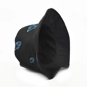 Détail d'un chapeau bob noir avec broderie papillon bleue et bord large en gros plan