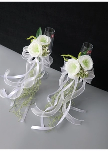 Detailed view of white silk roses and pearls with long ribbons on wedding wine glasses