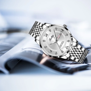 Detail of silver watch dial featuring roman numerals and dual date display on a magazine