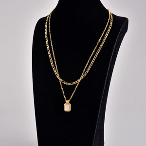 Double-layered golden necklace with figaro chain and white rectangular pendant detail