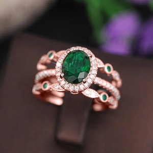 Close-up of luxury rose gold ring featuring a large oval green emerald and diamond halo