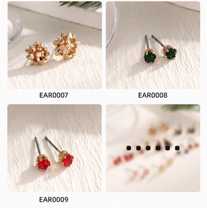 Macro detail of alloy stud earrings including gold bow, green and red gemstone designs