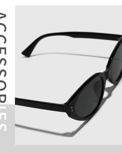 Detail shot of black cat-eye sunglasses featuring silver metal rivets and glossy finish
