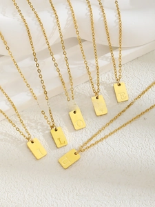 Détail de six pendentifs carrés dorés formant I LOVE U sur des chaînes en inox