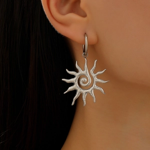Silver stainless steel sunburst earrings with spiral design worn by a female model