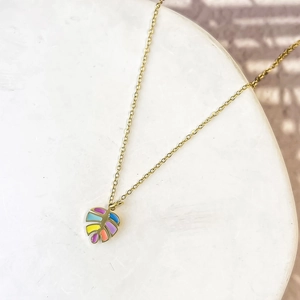 Detail of tropical monstera leaf pendant with colorful enamel on a golden chain necklace