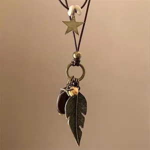Collier bohème vintage avec plumes en bronze antique et étoiles sur cordon marron