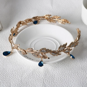 Detailed shot of golden leaf crown with sparkling rhinestones and blue teardrop gems