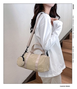 Detail of beige cylinder handbag with matching round pouch on a casual shoulder strap