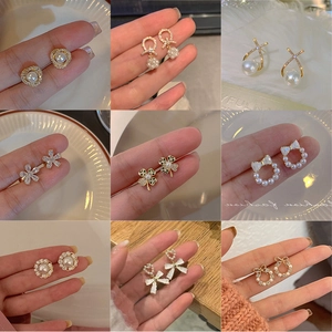 Collection of nine gold stud earrings with pearls, zircons, and floral camellia designs