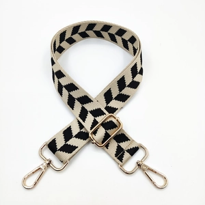 Detail of adjustable black and white geometric knit strap with gold metal swivel hooks