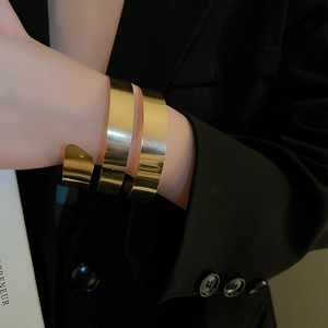 Primo piano di un ampio bracciale a spirale dorato con finitura lucida su modella