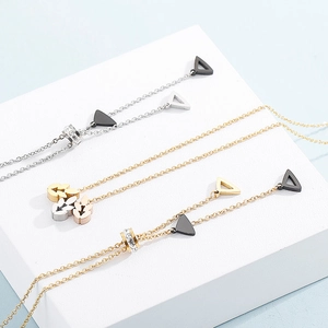 Macro shot of gold and silver layered necklaces with triangle charms on white blocks