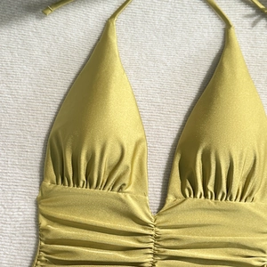 Detail of olive gold metallic ruched halter swimsuit top with elegant pleated texture
