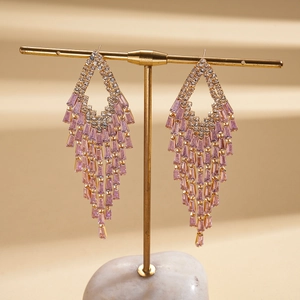Detail of gold tassel earrings with pink rectangular zircon and round clear crystals