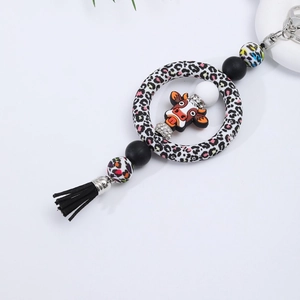 Close-up of silicone beaded keychain featuring cartoon cow charm and black tassel