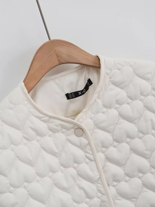 Detailed macro view of heart-shaped quilting and round neckline on white jacket