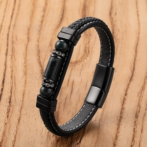 Detail of hand-woven black leather bracelet with magnetic clasp on a wood background