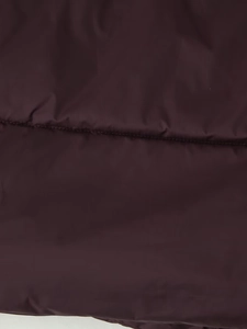 Detailed close-up of horizontal quilting and dark purple fabric texture on hooded jacket