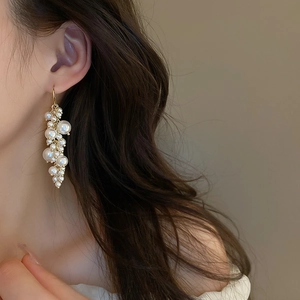 Detail of French vintage pearl tassel earrings with gold hooks on a model