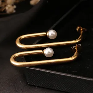 Minimalist U-shaped gold stud earrings with elegant pearls displayed on black velvet box