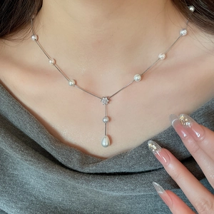 Detailed close-up of a zircon flower and teardrop pearl pendant on a Y-shaped necklace