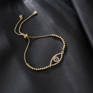 Detailed top view of gold Evil Eye bracelet with blue gemstone on black leather texture