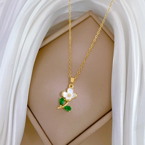 Close-up of a floral pendant necklace with white petals and green crystal leaves on silk