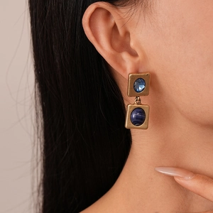 Close-up of woman wearing vintage gold square earrings with blue resin stones