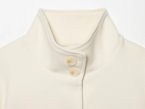 Detail of soft cream knit collar with two buttons and high funnel neck design