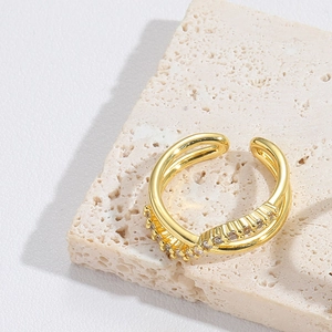 Detailed view of gold cross ring with double band design and zircon inlay on stone base
